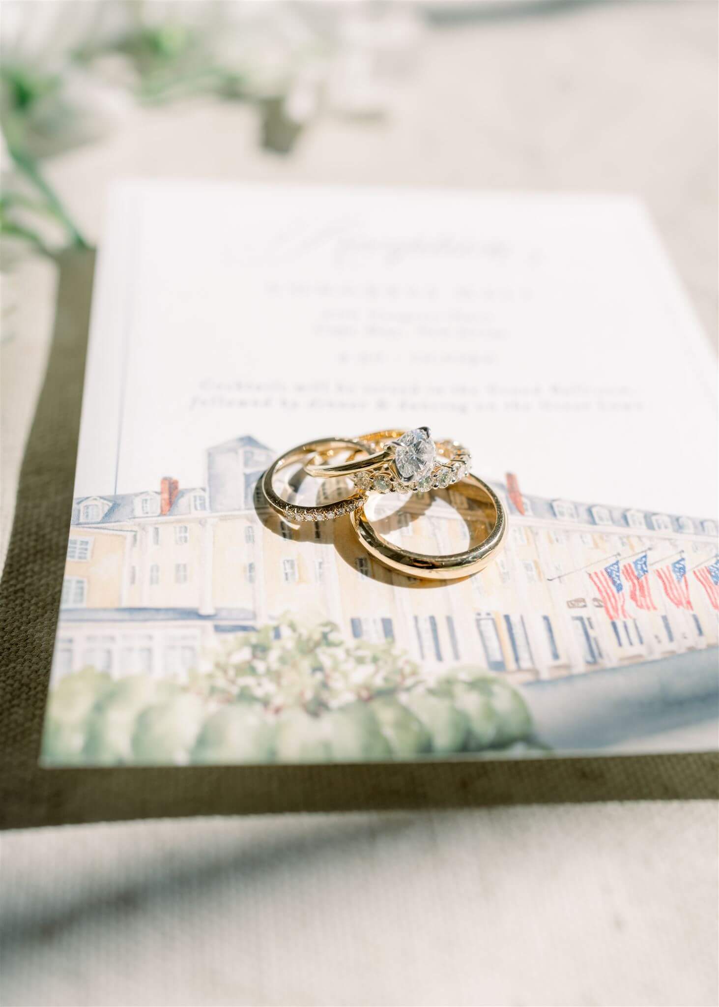Rings sitting on a wedding reception details card featuring custom watercolor illustration of Congress Hall